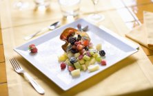 Closeup view of fresh fruit salad in crispy wafer on square plate — Stock Photo