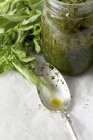 Closeup view of homemade Pesto in a jar with dirty spoon and fresh basil — Stock Photo
