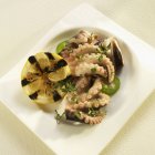 Vista ravvicinata del polpo marinato greco con erbe e limone alla griglia — Foto stock