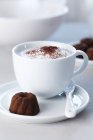 Cup of cappuccino and praline — Stock Photo