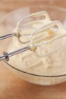Closeup view of cake mixture in a glass bowl and on the whisks of the mixer — Stock Photo