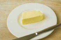 Vista de close-up de uma palmadinha de manteiga em uma chapa com uma faca — Fotografia de Stock
