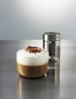 Cappuccino und eine Kakaostreuer — Stockfoto
