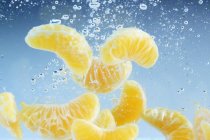 Segmentos de mandarina en el agua - foto de stock