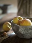 Fresh peaches in stone bowl — Stock Photo
