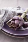 Carciofo fresco su piatto viola — Foto stock