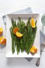 Green asparagus with oranges — Stock Photo
