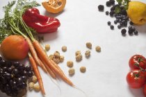Натюрморт з овочами, фруктами та сушеними солодкими каштанами, що лежать над білою поверхнею — стокове фото