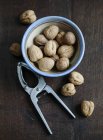 Walnuts and nutcracker on wooden — Stock Photo