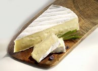 Brie con rodajas en tabla de cortar - foto de stock