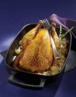 Roasted guinea fowl with onions in the roasting tin — Stock Photo