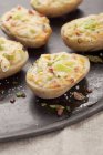 Stuffed baked potato halves with spring onions onblack wooden tray — Stock Photo
