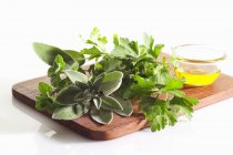 Still life with of fresh herbs and oil on wooden board — Stock Photo