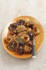 Vue surélevée des champignons marinés avec des feuilles de laurier et une fourchette sur une assiette orange — Photo de stock