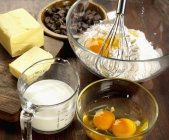 Closeup view of chocolate chips with butter, milk, flour and eggs — Stock Photo