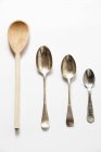 Closeup top view of wooden spoon and different sized metal spoons — Stock Photo