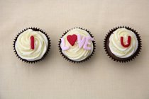 Closeup top view of declaration of love on three cup cakes — Stock Photo