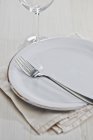 Closeup view of a place setting with a plate, a fork, a wine glass and a napkin — Stock Photo