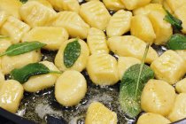 Vue rapprochée de la friture Gnocchi avec du beurre et de la sauge dans une poêle — Photo de stock