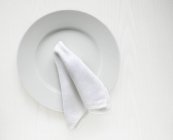 Вид зверху на білу тарілку і серветку — стокове фото