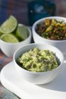Guacamole, bean dip and limes in white small bowls — Stock Photo