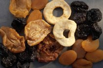 Різноманітність сушених фруктів над сірою поверхнею — стокове фото