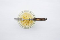 Chucrute em um jarro com um garfo no fundo branco — Fotografia de Stock
