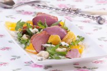 Closeup view of goose breast with oranges, grapes, grapefruit and rocket — Stock Photo
