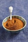 Closeup view of a small bowl of ground cinnamon with spoon — Stock Photo