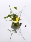 Aceite de hierbas casero en un recipiente de vidrio reflejado en una superficie brillante - foto de stock
