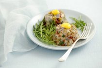 Herring tartar with dried tomatoes, pickled gherkins and quail eggs on white plate with fork — Stock Photo