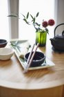 Daytime elevated view of an oriental arrangement featuring a bowl, chopsticks, noodles and tea — Stock Photo