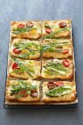 Mini tomato tarts with asparagus and rocket over grey surface — Stock Photo