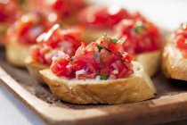 Bruschetta with tomato and basil on wooden desk — Stock Photo