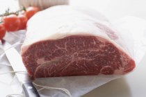 Fresh beef on paper with kitchen string — Stock Photo