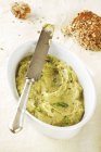 Hummus mit Frühlingszwiebeln in weißer Schale mit Messer über Tisch — Stockfoto