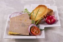 Closeup view of goose liver pate with toasts and vegetables — Stock Photo