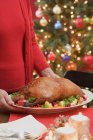 Woman serving whole roasted duck — Stock Photo