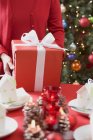 Woman putting Christmas parcel on table — Stock Photo