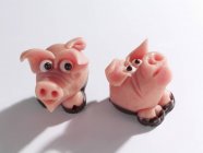 Closeup view of two marzipan pigs on white surface — Stock Photo