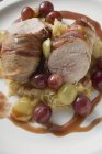 Pheasant breast with bacon, sauerkraut and grapes  on white plate — Stock Photo
