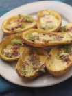 Baked potato skins with bacon and spring onions on white plate — Stock Photo