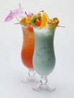 Deux longues boissons caribéennes avec des brochettes de fruits dans des verres — Photo de stock