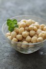 Chickpeas in a small glass bowl over grey surface — Stock Photo