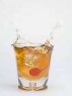 Крупный план кубика льда упал в бокал коктейля Манхэттена — стоковое фото