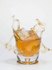 Кубик льоду падає в склянку чаю — стокове фото