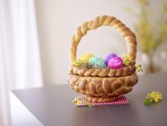 Vista de primer plano de la cesta de Pascua hecha de pan y llena de huevos de Pascua - foto de stock