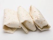 Primo piano vista di tre pacchi Tortilla sulla superficie bianca — Foto stock