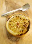 Closeup view of grilled grapefruit with spoon on wooden surface — Stock Photo