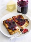 Closeup view of buttered halved toast with berry jam — Stock Photo